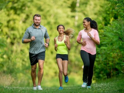 A multi-ethnic family (mother, father, daughter) getting exercise by going for a jog at the park.
