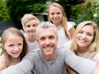 Happy Caucasian family taking a selfie outdoors and looking at the camera smiling