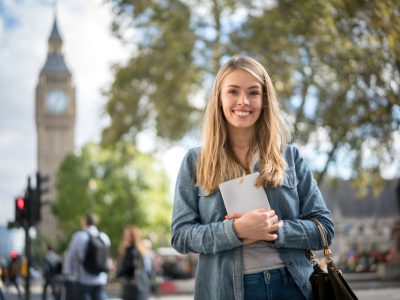 Happy female student in London holding a tablet computer and looking at the camera smiling