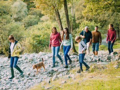 Three generation family are hiking together through the Lake District with their pet dog.